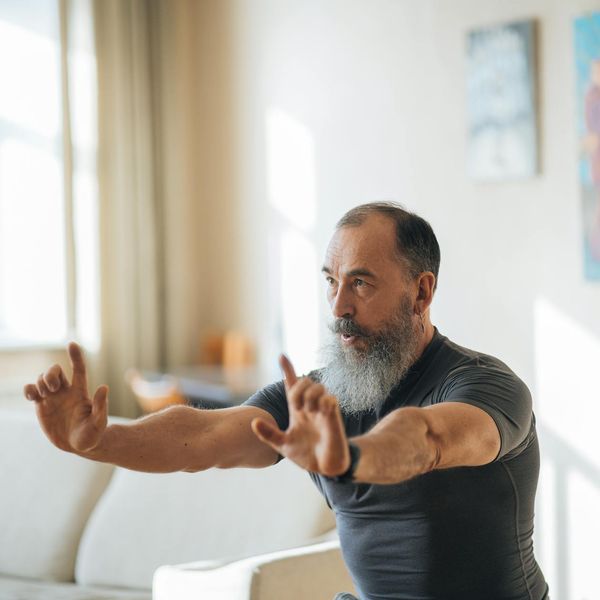 Man stretching during a morning yoga routine with orange accents.